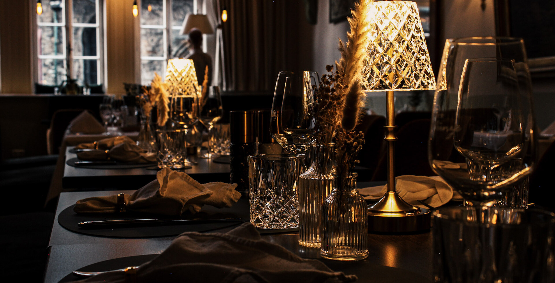 Stimmungsvoll gedeckter Restauranttisch bei warmem Kerzenlicht mit eleganter Tischdekoration und Gläsern im historischen Ambiente.