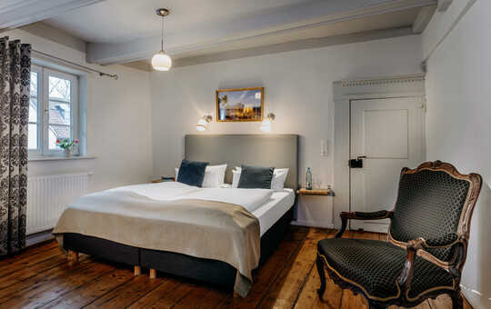 Schlafbereich der Gartensuite mit elegantem Doppelbett und stilvollen Sesseln.
