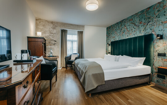 Komfortables Doppelzimmer mit großzügigem Bett, Schreibtisch und rustikalem Mauerwerk.